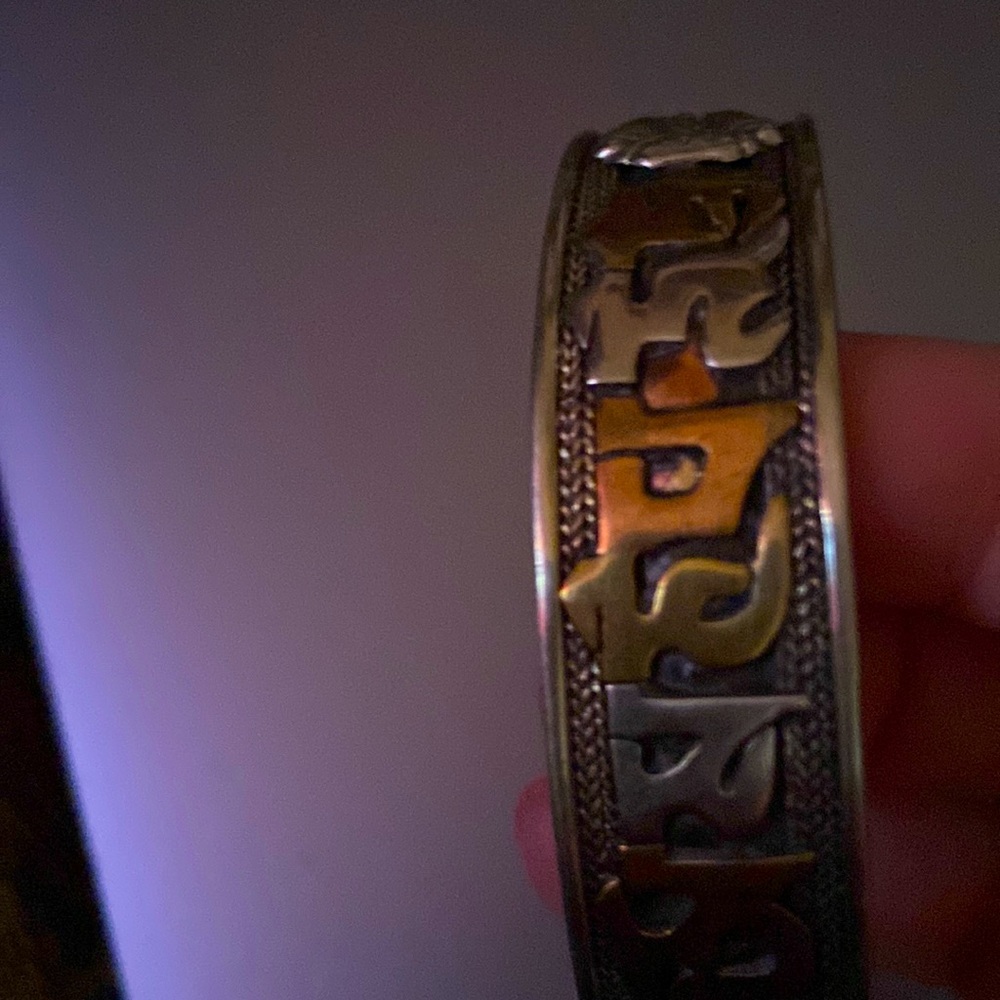 It is a bronze silver bangle type bracelet with unique symbols on it